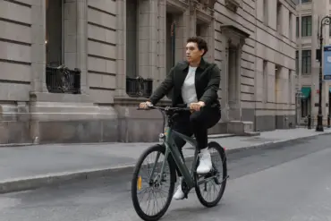 Mann fährt ein ENGWE N1 AIR E-Bike auf einer Straße in der Stadt, umgeben von Gebäuden.