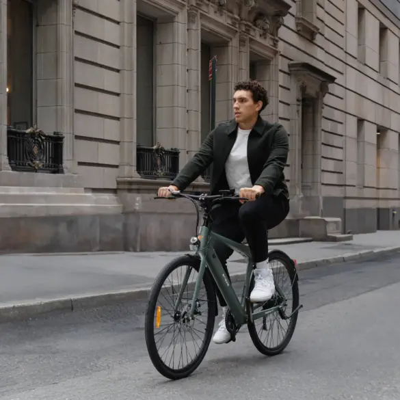 Mann fährt ein ENGWE N1 AIR E-Bike auf einer Straße in der Stadt, umgeben von Gebäuden.