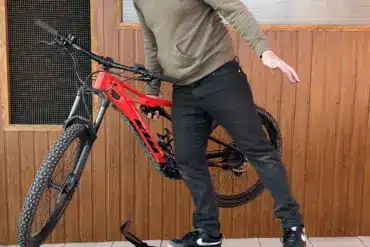 Ein Mann stellt ein rotes E-Bike auf einen schwarzen Ständer namens MXstyle.