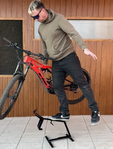 Ein Mann stellt ein rotes E-Bike auf einen schwarzen Ständer namens MXstyle.