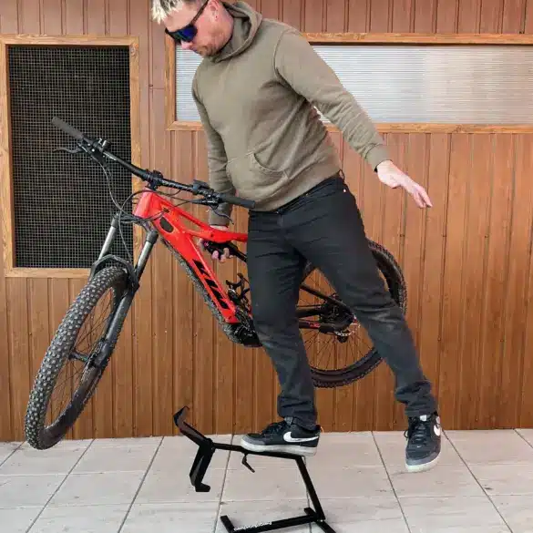 Ein Mann stellt ein rotes E-Bike auf einen schwarzen Ständer namens MXstyle.