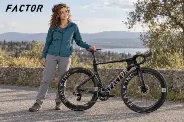 KI-generiertes Bild: Frau mit Aero-Rennrad von Factor auf einem Weg oberhalb eines Sees