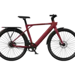 Weinrotes AMANO S900 City-E-Bike mit schwarzem Gepäckträger und Felgen, auf schwarzem Hintergrund.
