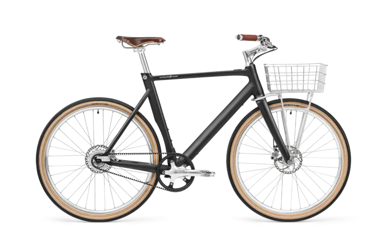 Schwarz mattes Arthur Cruiser E-Bike mit braunem Ledersattel, braunen Griffen und einem silbernen Frontkorb, ausgestattet mit Schutzblechen und einem Zahnriemenantrieb.