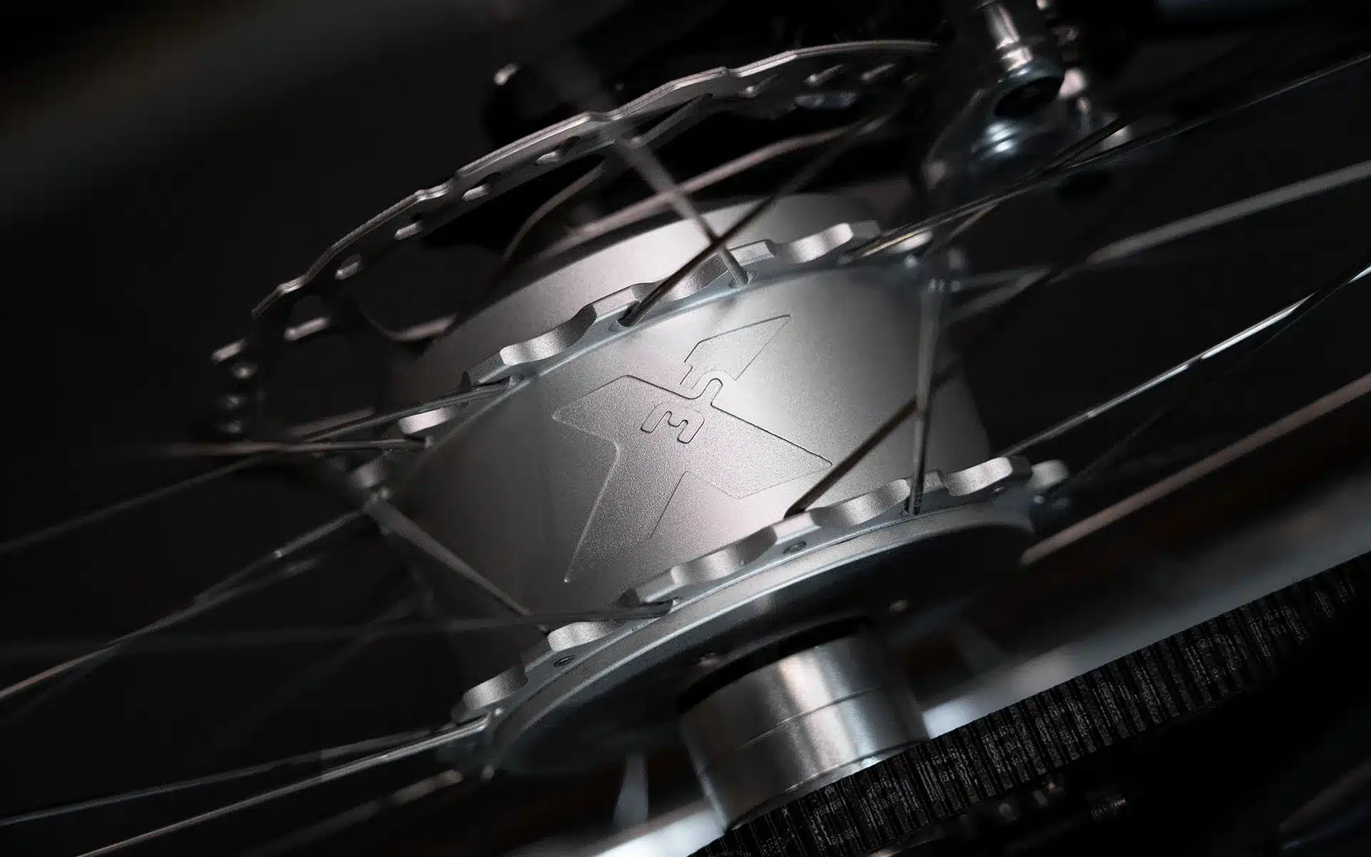 Nahaufnahme des silbernen Hinterradnabenmotors eines Schindelhauer Arthur Cruiser E-Bikes, mit sichtbarem Logo und Zahnriemen.