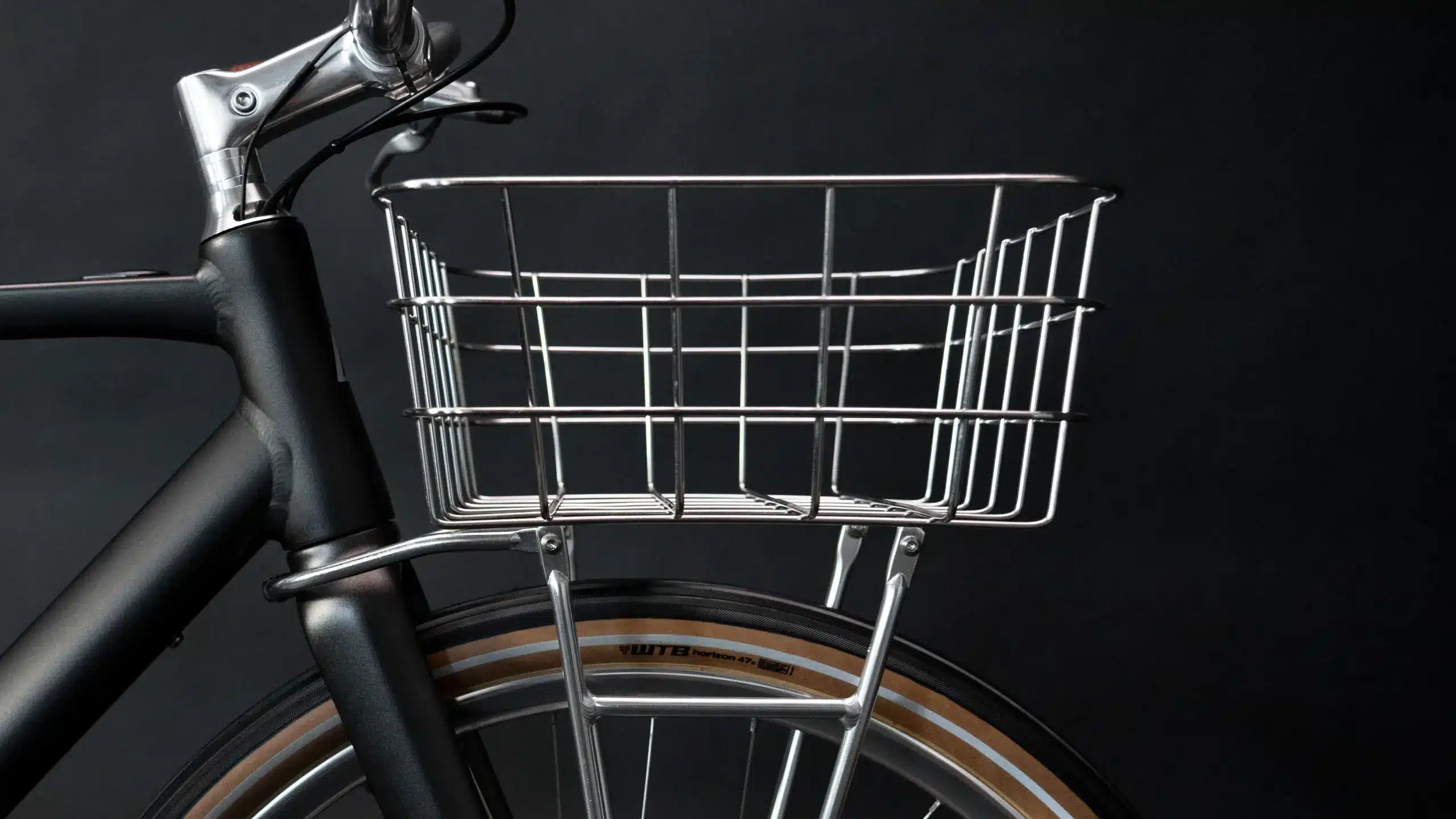 Detailaufnahme eines schwarzen Arthur Cruiser E-Bikes mit silbernem Frontkorb und braun-schwarzem Reifen