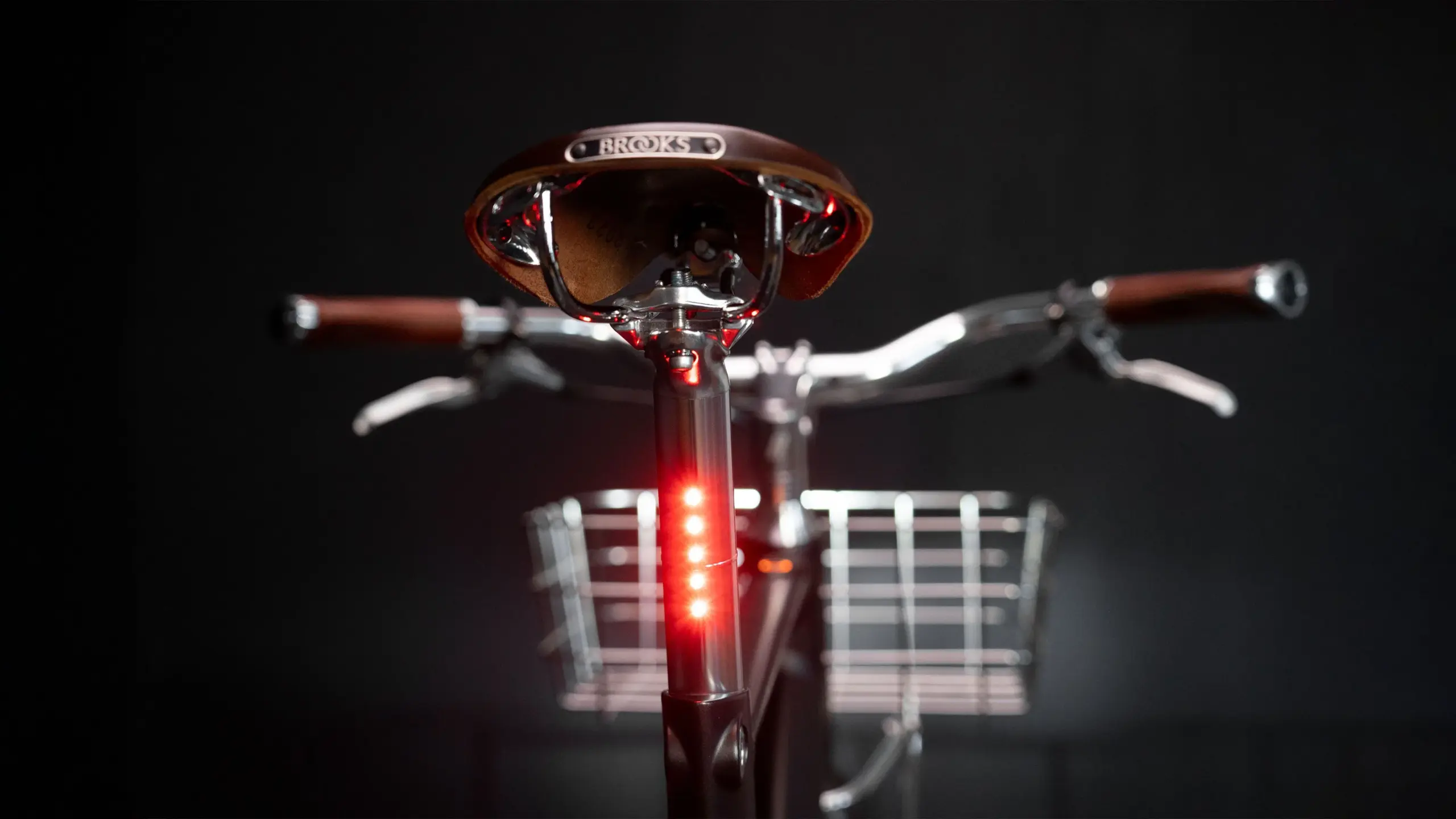 Vorderansicht eines Arthur Cruisers E-Bikes mit Fokus auf den Vorbau, den klassischen Brooks-Ledersattel, die Lenkergriffe und das integrierte rote Rücklicht.