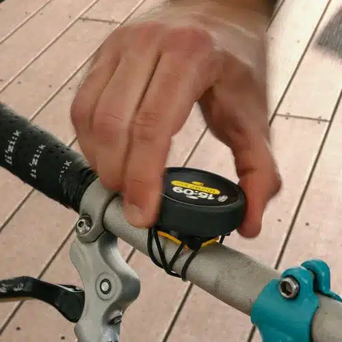 Mann montiert einen runden, schwarzen Fahrradcomputer mit gelbem Display, der die Zeit
