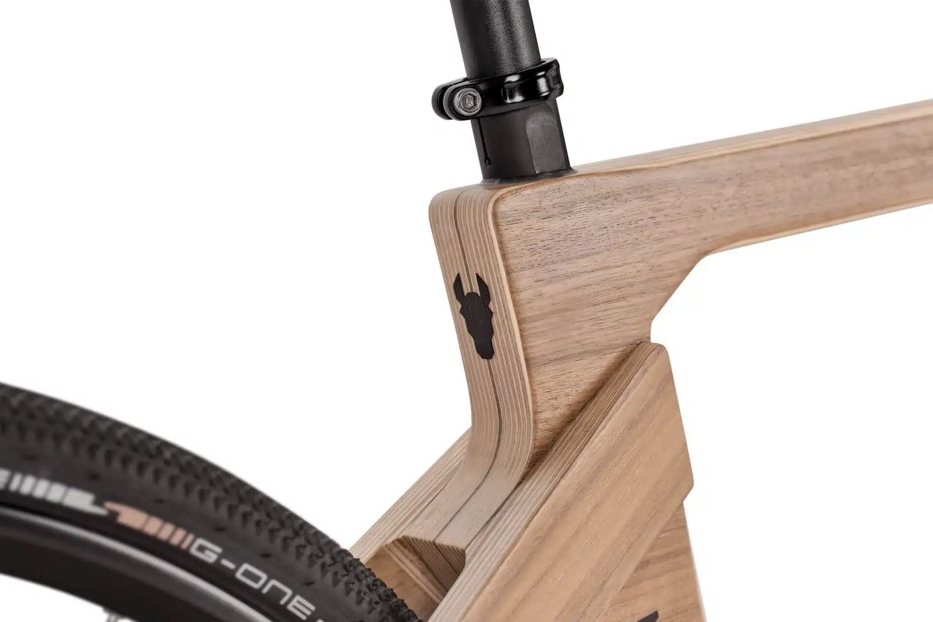 Nahaufnahme des Sitzrohrbereichs eines Gravelbikes mit einem Rahmen aus Holz. Ein schwarzes Logo in Form eines Eselskopfes ist auf dem Rahmen angebracht.