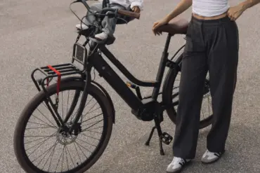 Ein schwarzes LEKKER Jordaan Urban eBike mit einem Kind im Front-Kindersitz. Eine Frau steht daneben.