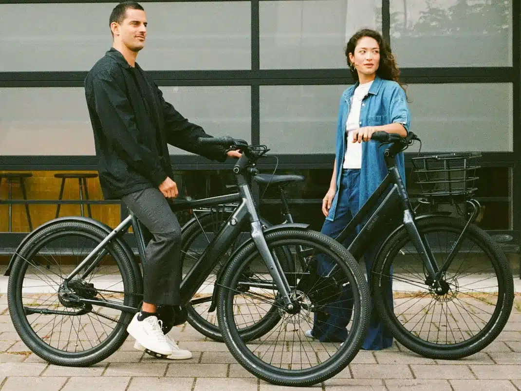 Mann und Frau stehen nebeneinander mit ihren jeweiligen dunkelgrauen E-Bikes.