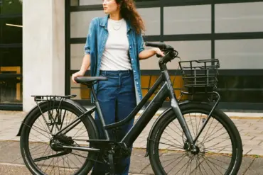Frau mit dunkelgrauem Lekker Limited Edition GTS E-Bike mit Gepäckträgern und Frontkorb.