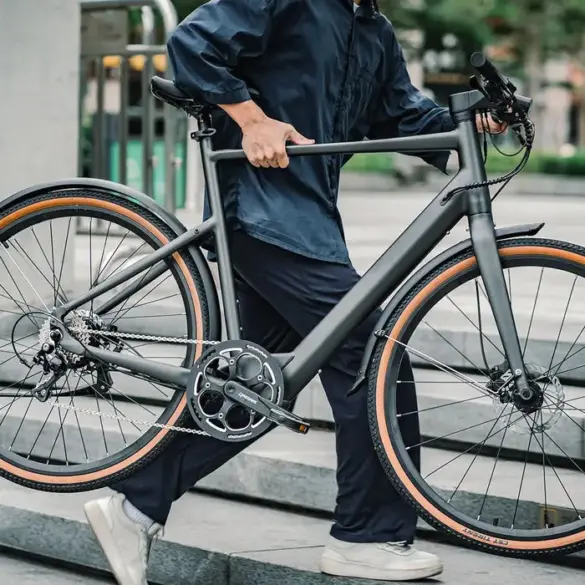 Schlankes, matt-graues Fiido C21 E-Bike, getragen von einer Person, mit Fokus auf die klare Linienführung und den Drehmomentsensor.