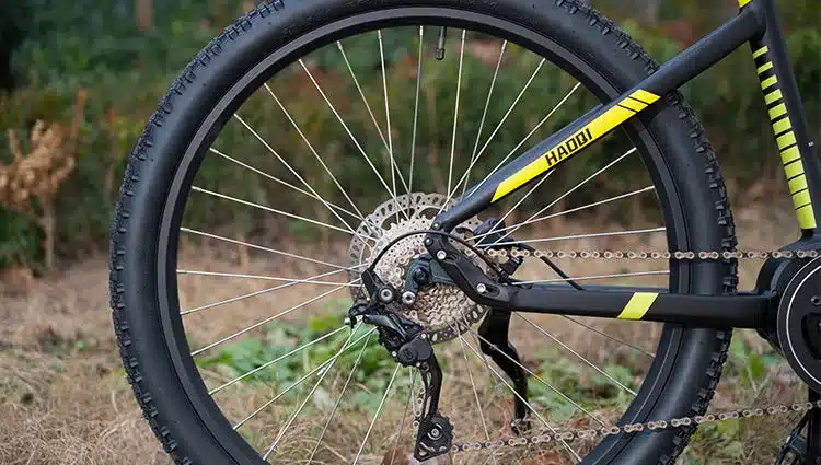 Nahaufnahme des Hinterrads eines schwarzen E-MTB mit gelben Akzenten, wobei die Schaltung, Kassette und der Reifen gut sichtbar sind.