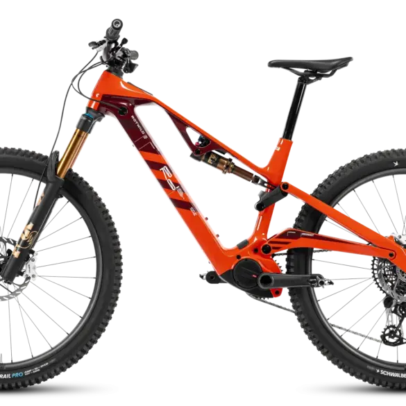 Orangefarbenes R.XX ULTIMATE Elektro-Mountainbike mit schwarzen Akzenten, goldener Federgabel und roten/weißen Logos auf dem Rahmen, präsentiert vor einem neutralen Hintergrund.