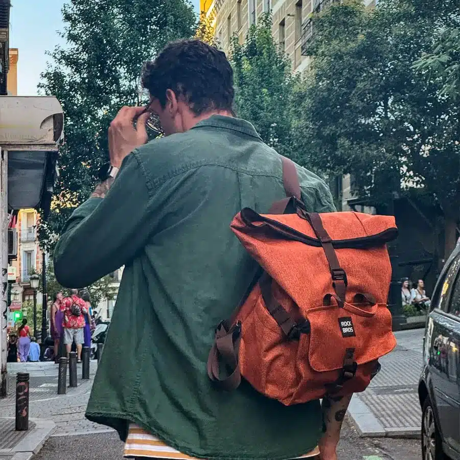 Ein Mann mit dunklem Hemd trägt eine orangefarbene ROCKBROS Fahrradtasche auf dem Rücken, die als Rucksack genutzt wird.