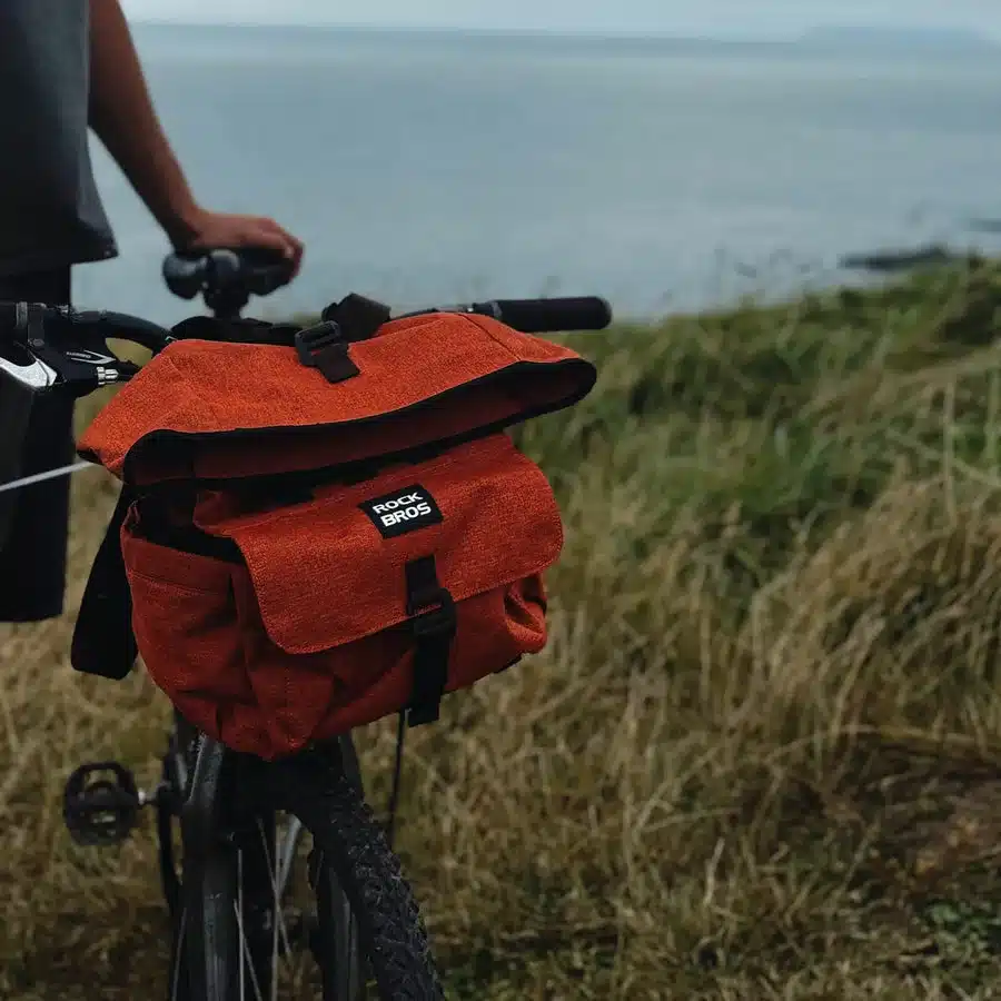 Orangefarbene ROCKBROS Fahrradtasche mit dem Logo auf dem Vorderfach, befestigt am Lenker eines Brompton-Fahrrads.