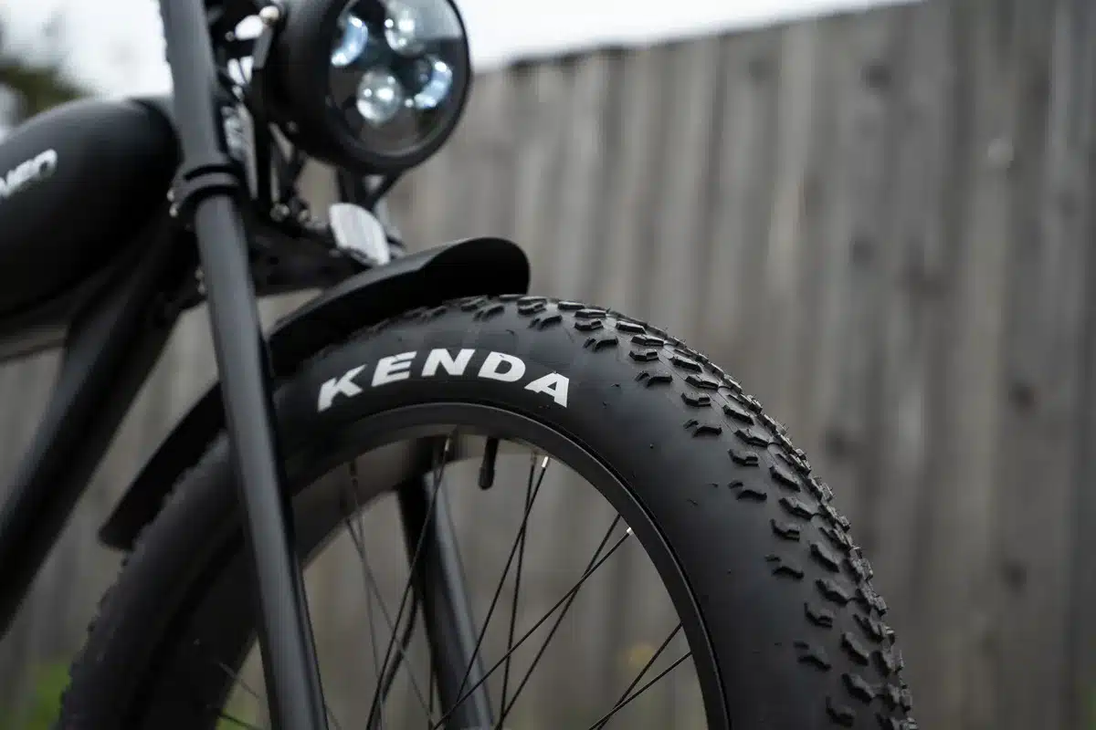 Detailansicht des Vorderrads eines schwarzen Varaneo Café Racer E-Bikes mit breitem Kenda-Reifen und silbernem