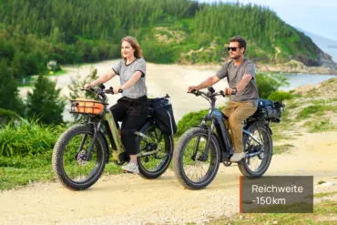 Ein Mann und eine Frau fahren nebeneinander auf E-All-Terrain-Bikes mit Fatbike-Reifen in einer landschaftlich reizvollen Küstenregion.