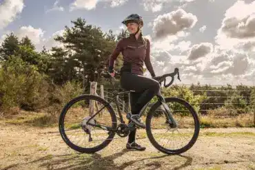 Frau auf einem BESV JGR 1.1 E-Gravel Bike im Freien, bereit für Abenteuer.