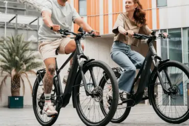 Mann und Frau fahren nebeneinander auf schwarzen AERES Leuven SX 9 Mid Step E-Bikes.