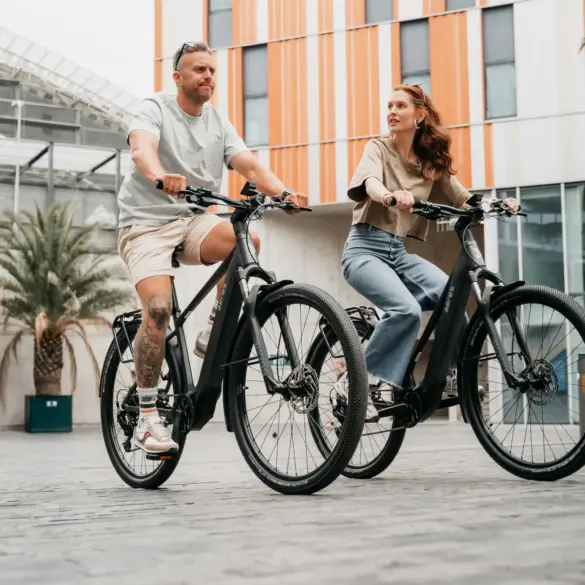 Mann und Frau fahren nebeneinander auf schwarzen AERES Leuven SX 9 Mid Step E-Bikes.