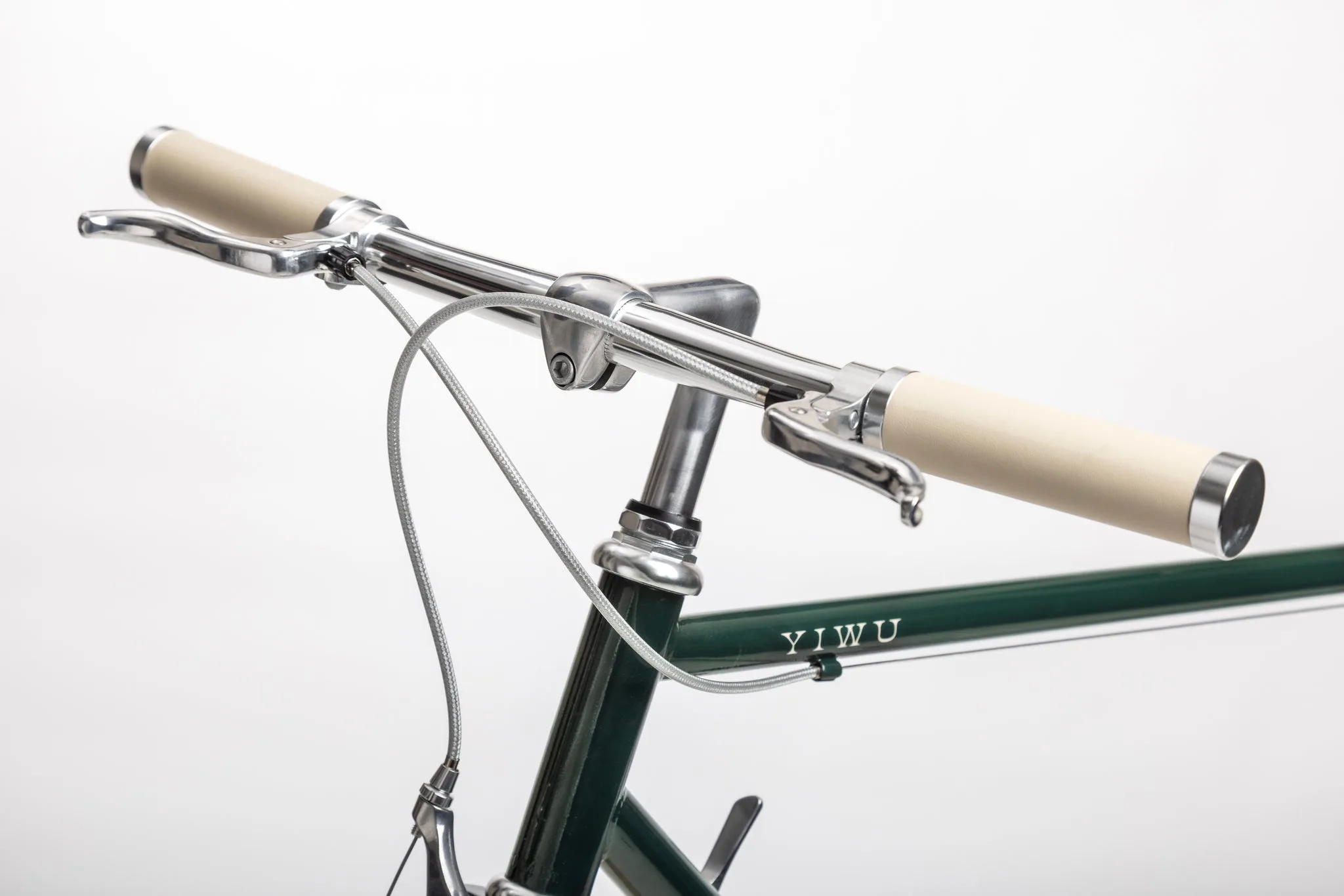 Detailansicht des Lenkers und des Steuerrohrs eines dunkelgrünen YIWU+ Citybikes mit cremefarbenen Griffen und silbernen Bremshebeln.