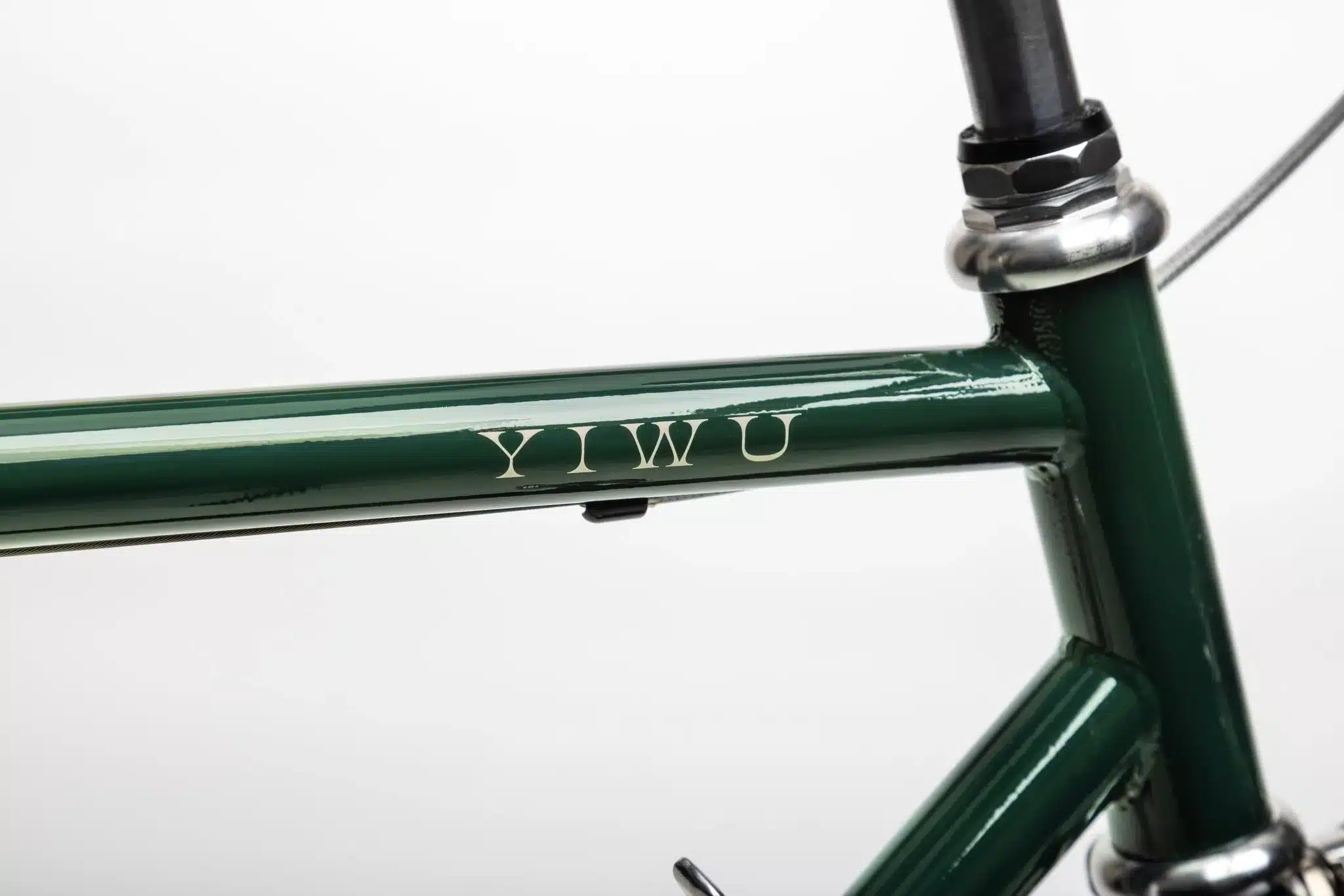 Detailaufnahme des YIWU+ Racing Green Citybikes, zeigt den Schriftzug 'YIWU' auf dem dunkelgrünen Stahlrahmen.