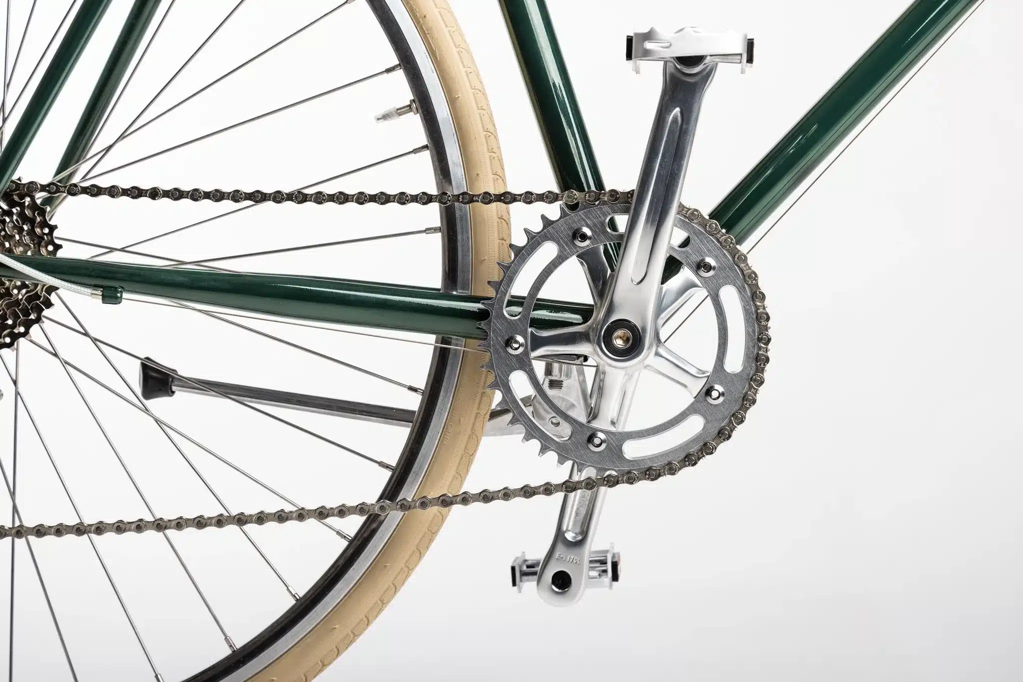 Nahaufnahme der Fahrradkette, des Kettenblatts, der Kurbel und eines Teils des Hinterrads eines grünen Stadtrads.