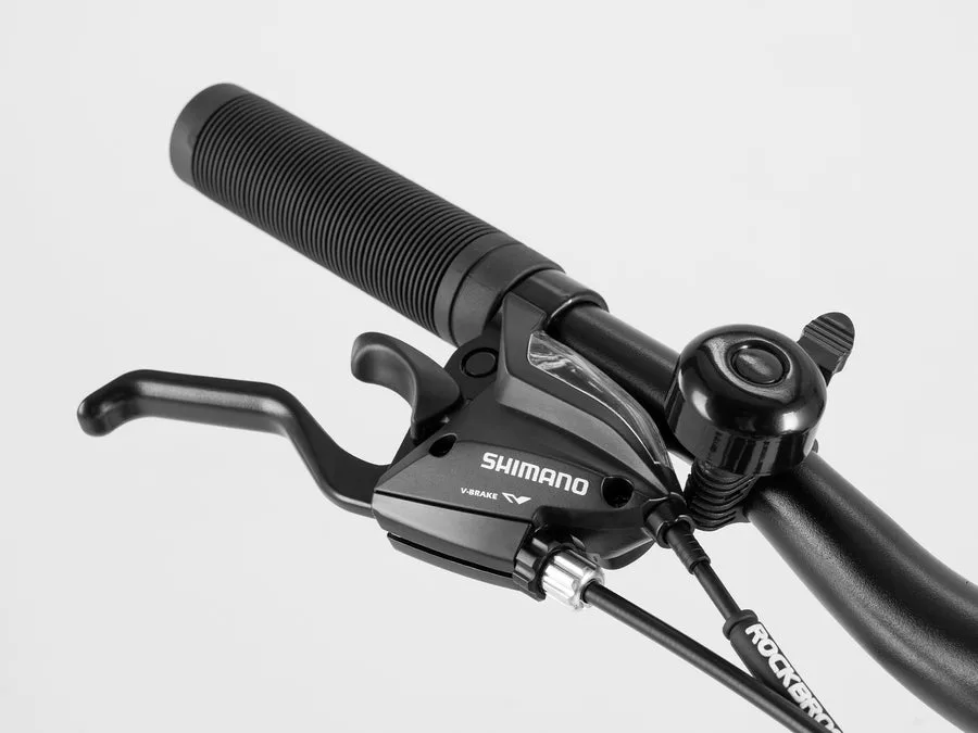 Nahaufnahme eines Fahrradlenkers mit schwarzem Griff, Bremshebel und Shimano-Schalthebel, sowie einer kleinen schwarzen Fahrradklingel.