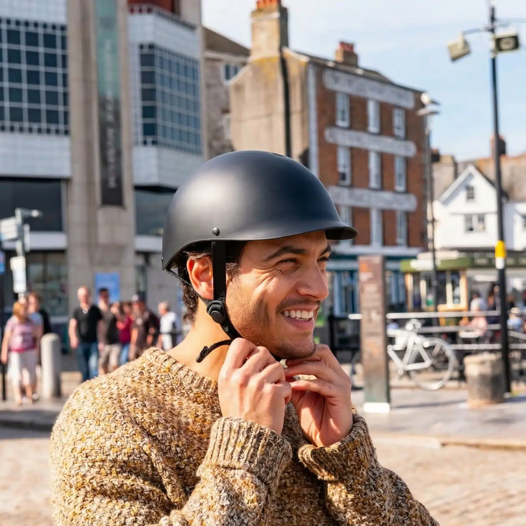 Mann mit schwarzem, mattem City-Helm und Wollpullover, stellt den Verschluss ein.