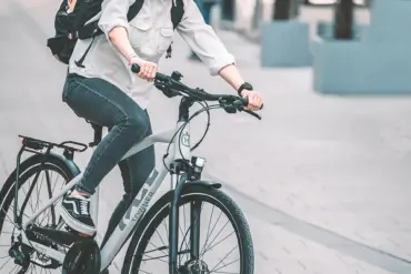 Frau fährt ein Husqvarna Towner B3 Urban-Bike mit Gepäcktasche auf dem Rücken, Helm und Sonnenbrille tragend.