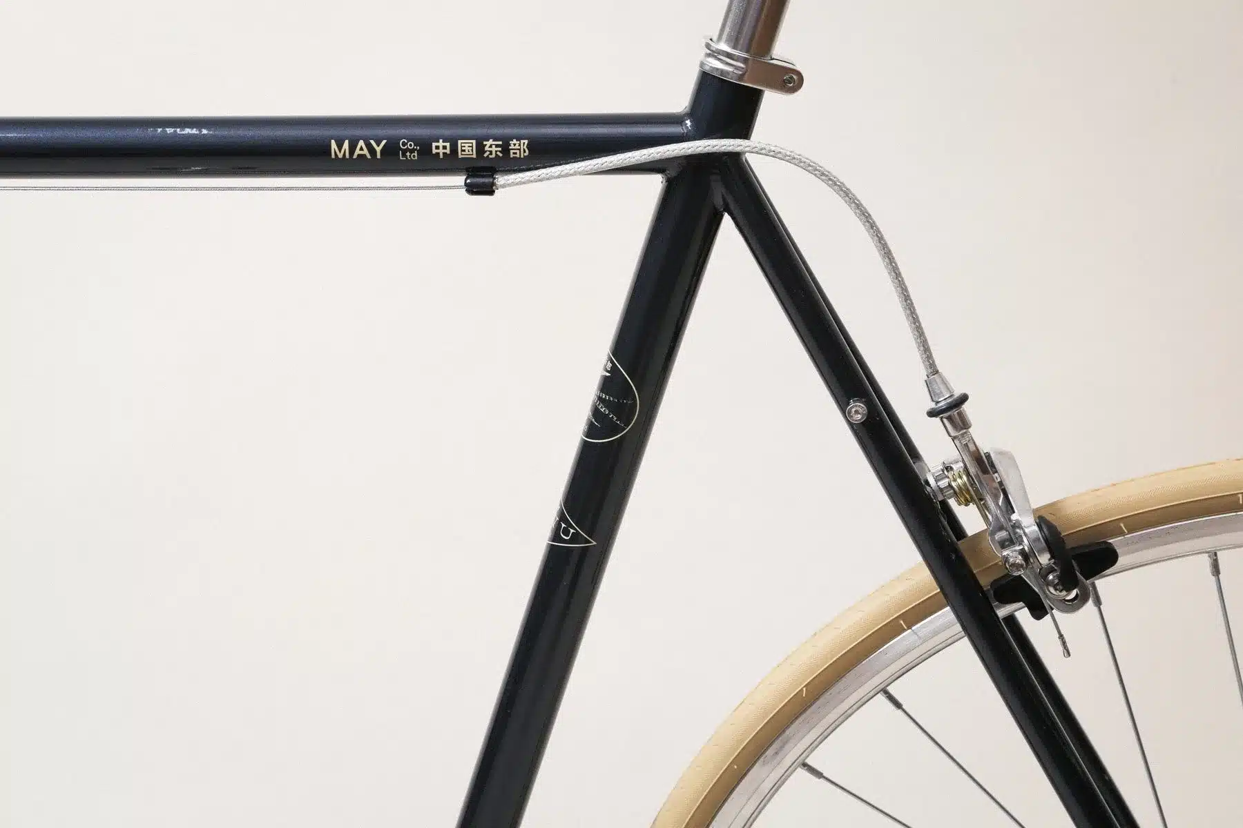 Detail des schwarzen Rahmens eines YIWU Night Blue Citybikes mit silbernem Schriftzug 'MAY Co., Ltd. 中国东部' und einer silbernen Bremszugführung.